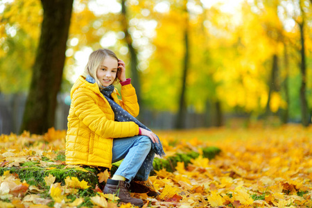 可爱的小女孩，在美丽的秋日乐趣。快乐的孩子在秋天公园玩。孩子收集黄色秋天的落叶。儿童秋季活动