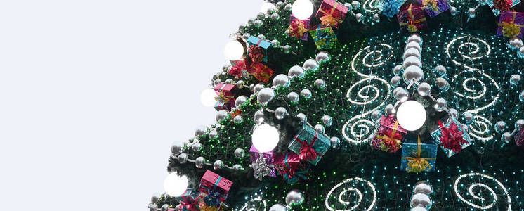 一棵巨大的圣诞树的碎片, 上面有许多装饰品礼品盒和夜光灯。一张装饰圣诞树特写照片与复制空间