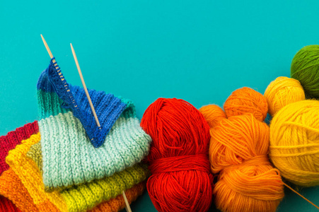 编织彩虹围巾和帽子。篮子与羊毛球, 针织针。蓝色背景。最喜欢的工作是爱好