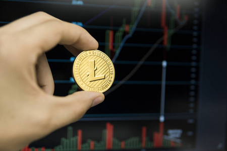 男性商人手持 Litecoin 硬币的背景下的增长图在屏幕上的笔记本电脑。虚拟货币和财务增长概念的图表背景。Litecoins 
