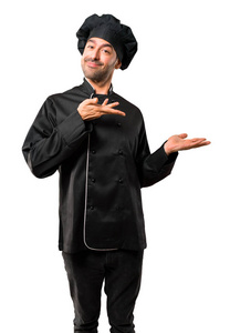 穿黑色制服的厨师长手伸向一旁, 微笑着呈现和邀请来到与世隔绝的白色背景