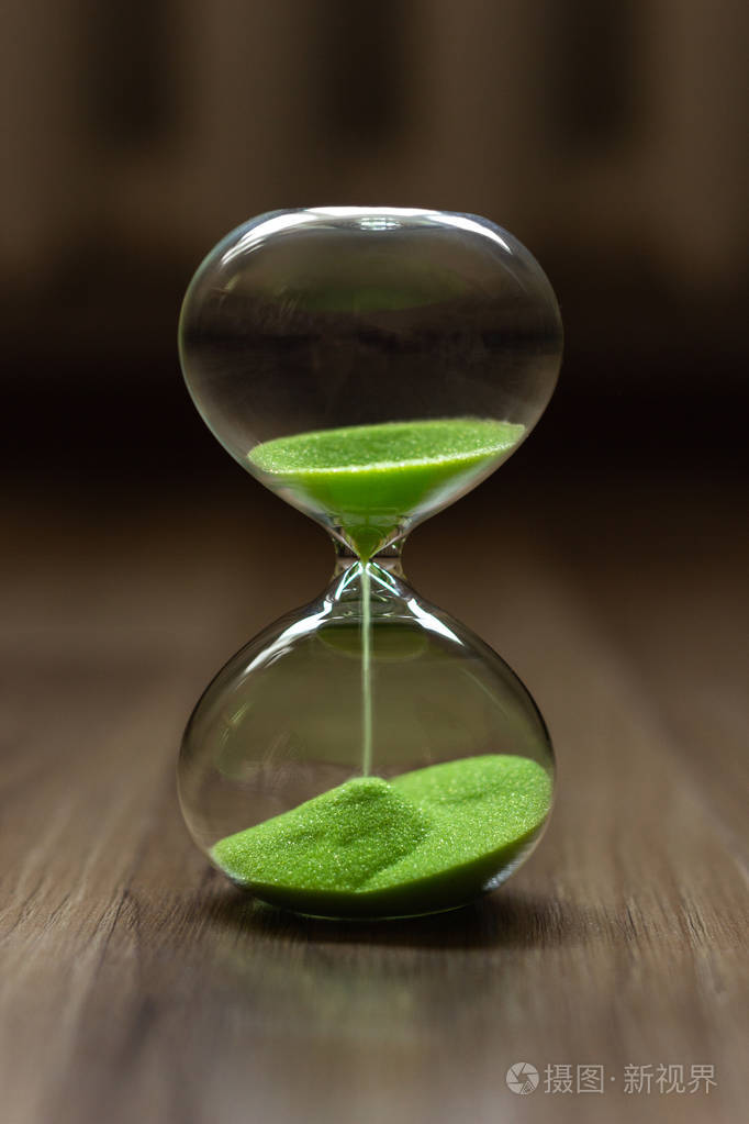 沙漏与绿色沙子在一个模糊的背景