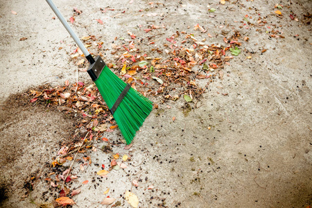 人们在秋天的花园里扫扫帚叶。五颜六色的干燥叶子 红色, 橙色, 黄色, 绿色谎言在公园在草坪和路。秋季清洁, 在花园工作。许多