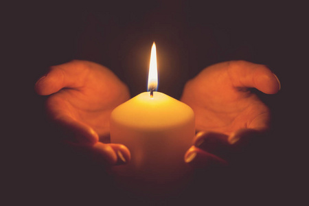 老式的手捧着燃烧的蜡烛在黑暗中的语气照片