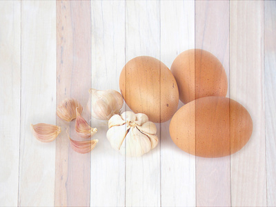 鸡蛋和大蒜对木制背景看起来像绘画