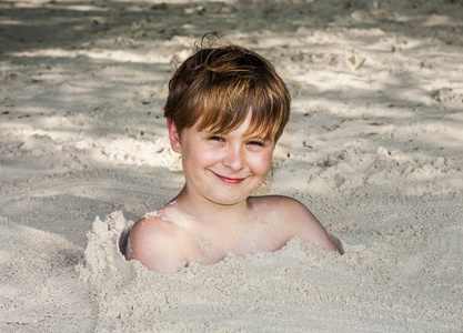 由细砂在海滩的小男孩