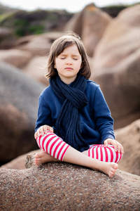 健康瑜伽儿童，闭着眼睛坐在花岗岩石头上