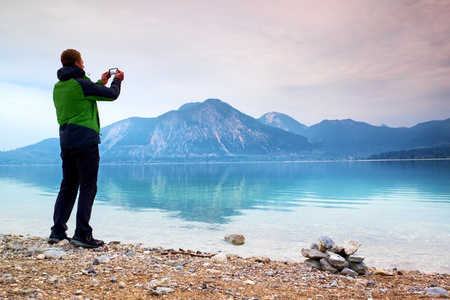 高个子男人举行手机 拍照湖山秋色