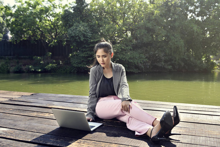 在户外使用笔记本电脑的年轻亚洲商务妇女