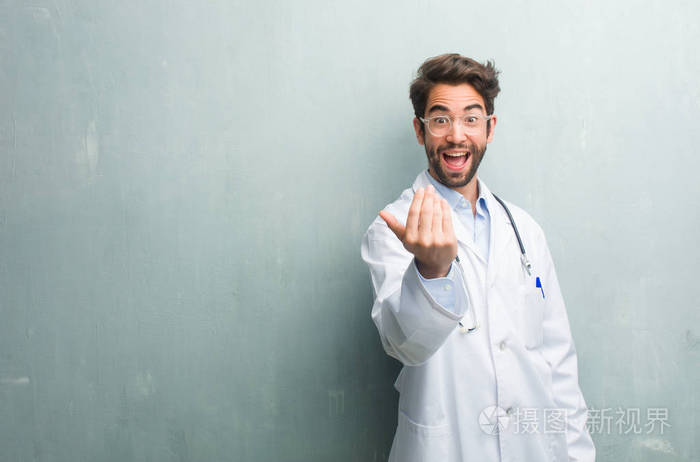 年轻友好的医生人对一个垃圾墙与复制空间邀请来, 自信和微笑做手势与