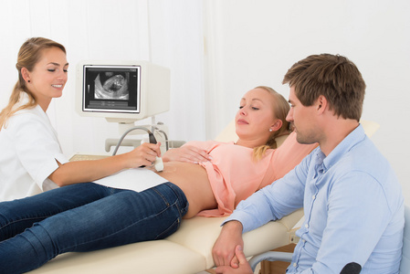 医生在孕妇的肚子上移动超声传感器