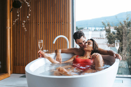 美丽的情侣享受着香槟的放松沐浴