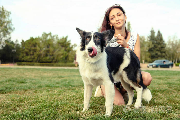 女孩与边境牧羊犬狗在公园散步