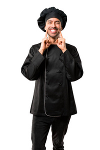 穿着黑色制服的厨师男士微笑着, 用手指在孤立的白色背景上, 带着愉快而愉快的表情。