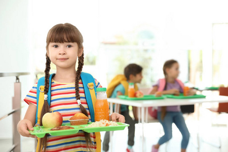 在学校食堂里拿着健康食物的女孩托盘