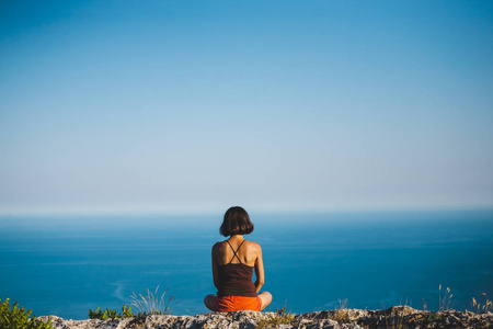 日落时 一个女孩坐在山顶上 一个女人从事瑜伽 坐在莲花的位置 冥想离文明很远 漂亮的女背 山和海 的景色 照片 正版商用图片 摄图新视界