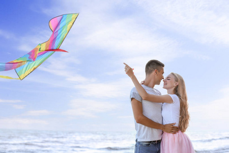 快乐的年轻夫妇在海上放飞风筝图片