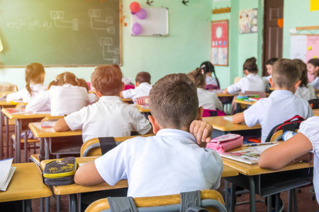 从后面的教室里坐下来听老师讲课的一群学生照片