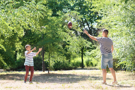 小男孩与他的爸爸在户外踢橄榄球