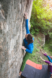 登山者是在自然的抱石。女孩爬上一块大石头。女人做户外运动。运动员从事户外活动
