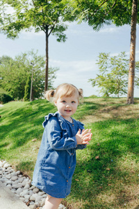 小3岁的女孩穿着蓝色牛仔裤在一个温暖的阳光明媚的日子在公园散步