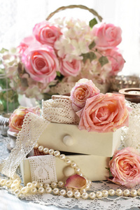 破旧别致的风格室内装饰花边和粉红色的玫瑰在桌子上的小抽屉