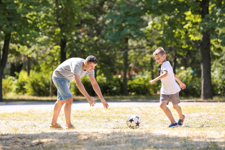 小男孩与他的爸爸在户外踢足球