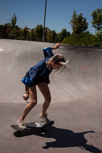 都市风格的年轻妇女做滑板在 skatepark