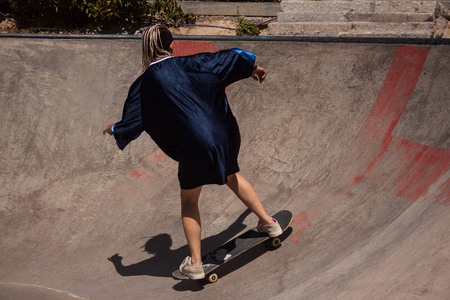 都市风格的年轻妇女做滑板在 skatepark