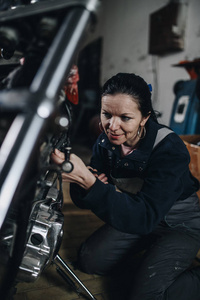 坚强而有价值的女人在汽车和摩托车修理厂做艰苦的工作