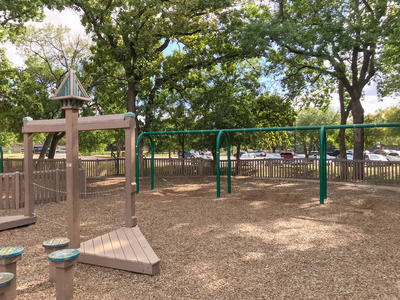 公共木制儿童游乐场象堡垒或城堡以分开的部分为不同的年龄。戏剧集结构在美国德克萨斯州的大树茂盛的夏天叶子绿色和云彩蓝天