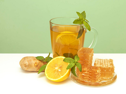 感冒最好的良药。蜂蜜, 柠檬, 姜和薄荷的玻璃杯中的草药茶