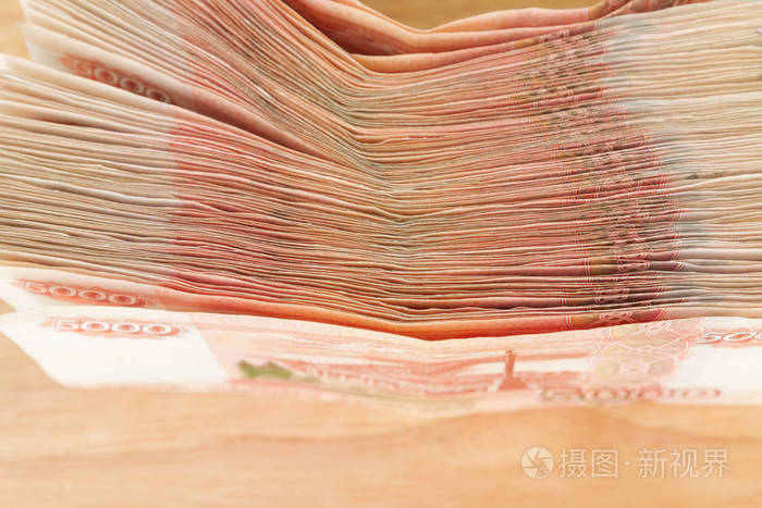 一大堆俄罗斯钞票5000卢布躺在一张木桌上