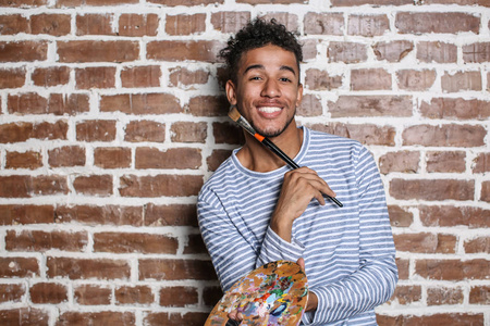 年轻的非洲裔美国艺术家与调色板和刷砖墙