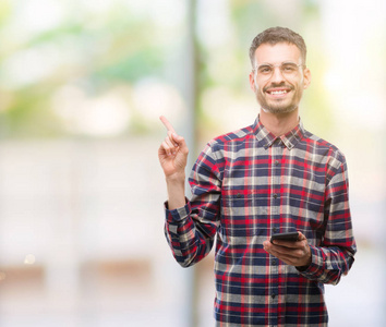 年轻时髦的成人男子手持智能手机非常高兴地指着手和手指的一侧