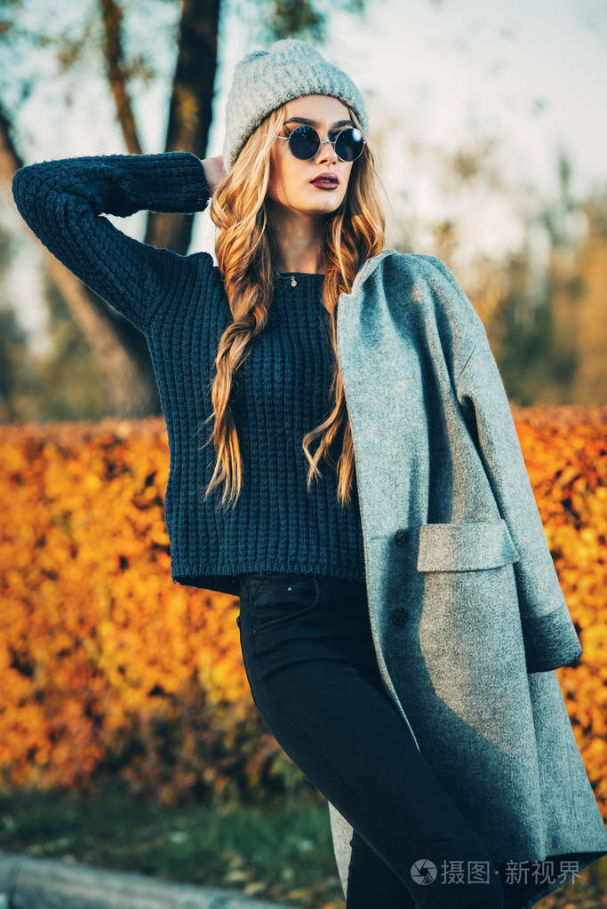 季节性的秋季时装.现代的年轻女性,穿着时尚保暖的衣服摆在秋天的公园