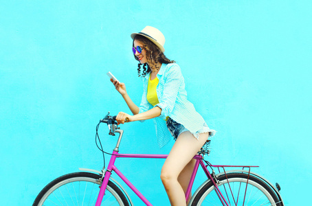 相当酷的微笑女人使用智能手机复古自行车。