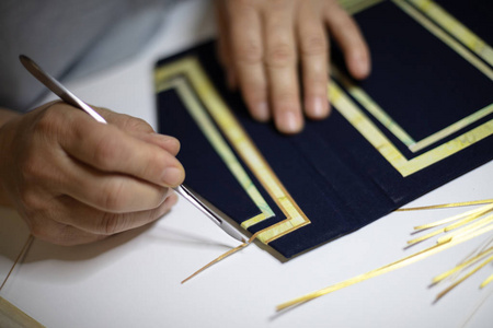 书籍活页夹手工作在他的工作坊的一个精装书的蓝色封面图案在他的手上