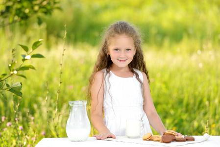 可爱小女孩微笑着吃早饭喝牛奶户外夏天