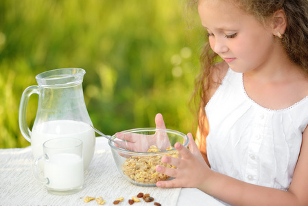 关闭了的可爱女孩吃早餐，喝牛奶室外肖像。谷类食品，健康的生活方式