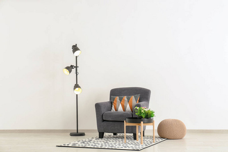 舒适的扶手椅, 带桌子, 脚凳和落地灯, 靠近轻墙