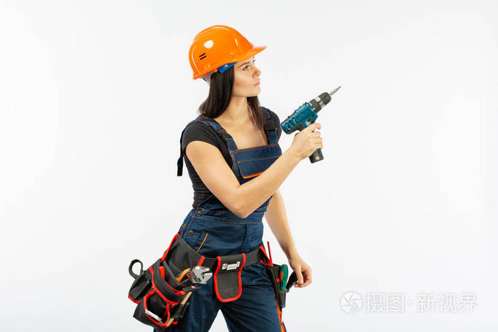 年轻女子与 toolbelt 使用 driil 和一些电动工具, 她的工作在家里.