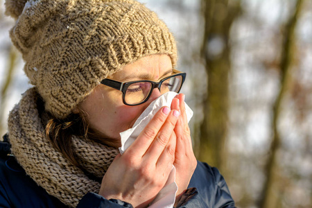 秋季流感冷鼻子的女人在纸巾里吹.