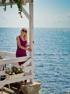 一个戴眼镜的金发女孩站在海边的凉亭里