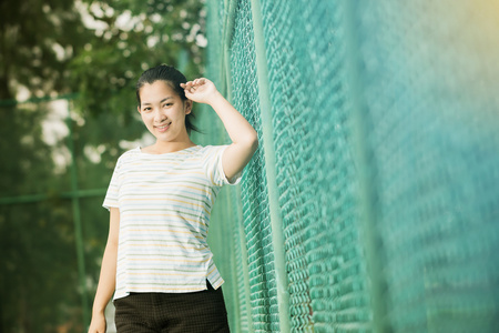 亚洲女性放松和微笑站在网球场上
