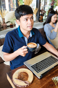 帅男人享受咖啡的咖啡馆 w 的亚洲微笑着的肖像