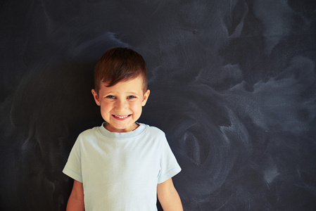 小男孩紧靠着黑板真诚微笑图片