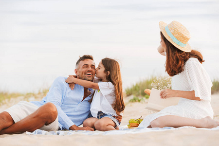幸福的家庭与父亲, 母亲, 女儿在海滩野餐, 拥抱