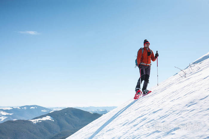 登山运动员在雪地鞋背着一个背包.在冬天的山上旅行.
