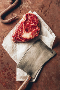厨房内桌上的生肉牛排金属钩和切刀的顶部视图